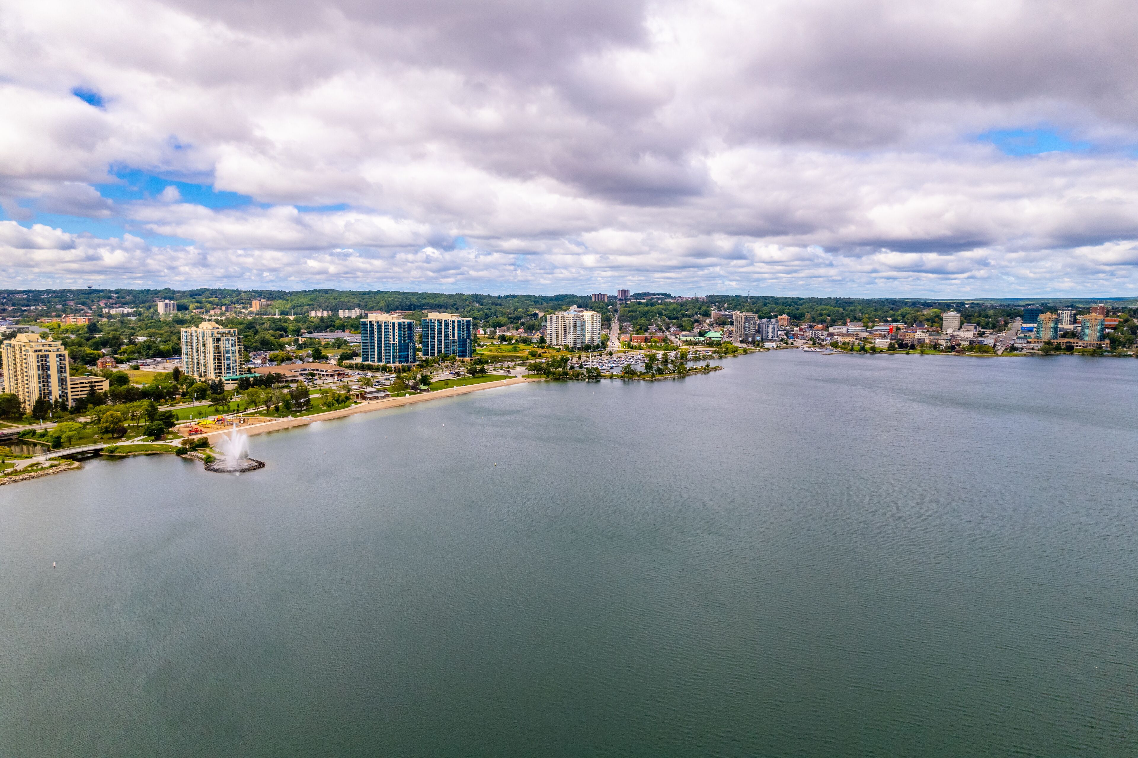A cityscape with a large body of water, several high-rise buildings, and a park area.
