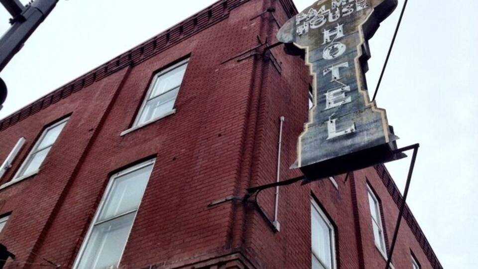 A red brick building with a large, tilted sign that reads "Palmer Hotel."