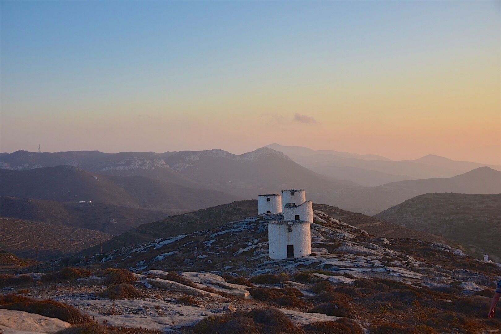 A mountainous landscape with a white tower on a hill.