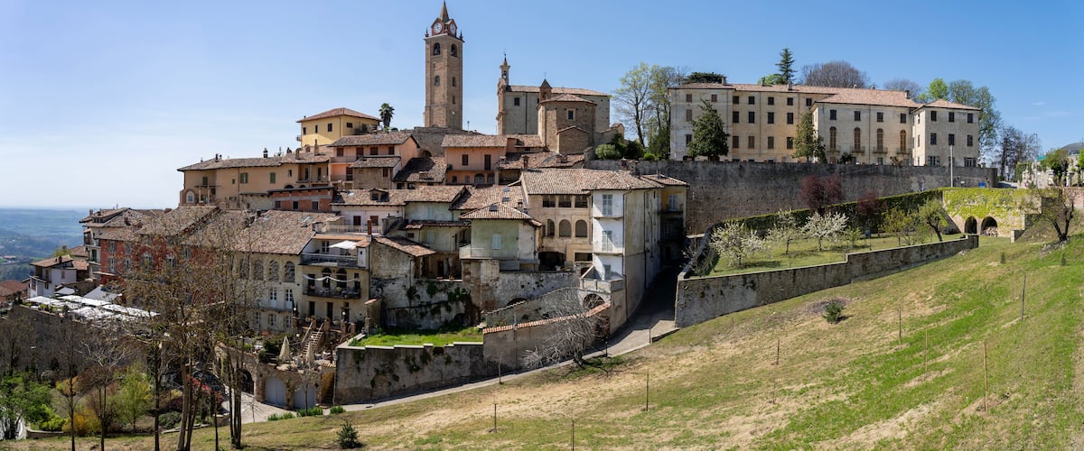 A historic town with a prominent tower, terracotta-roofed buildings, and a stone wall.