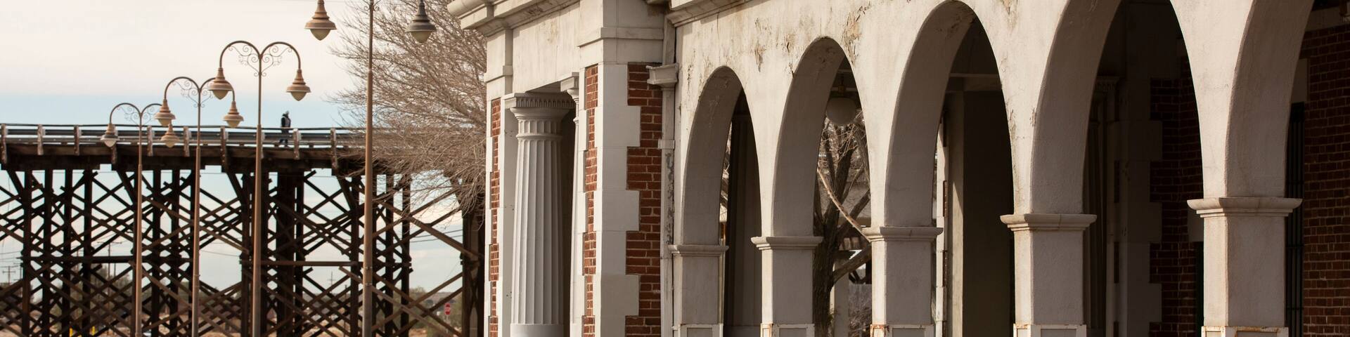 A series of arches and a metal structure with hanging lamps.