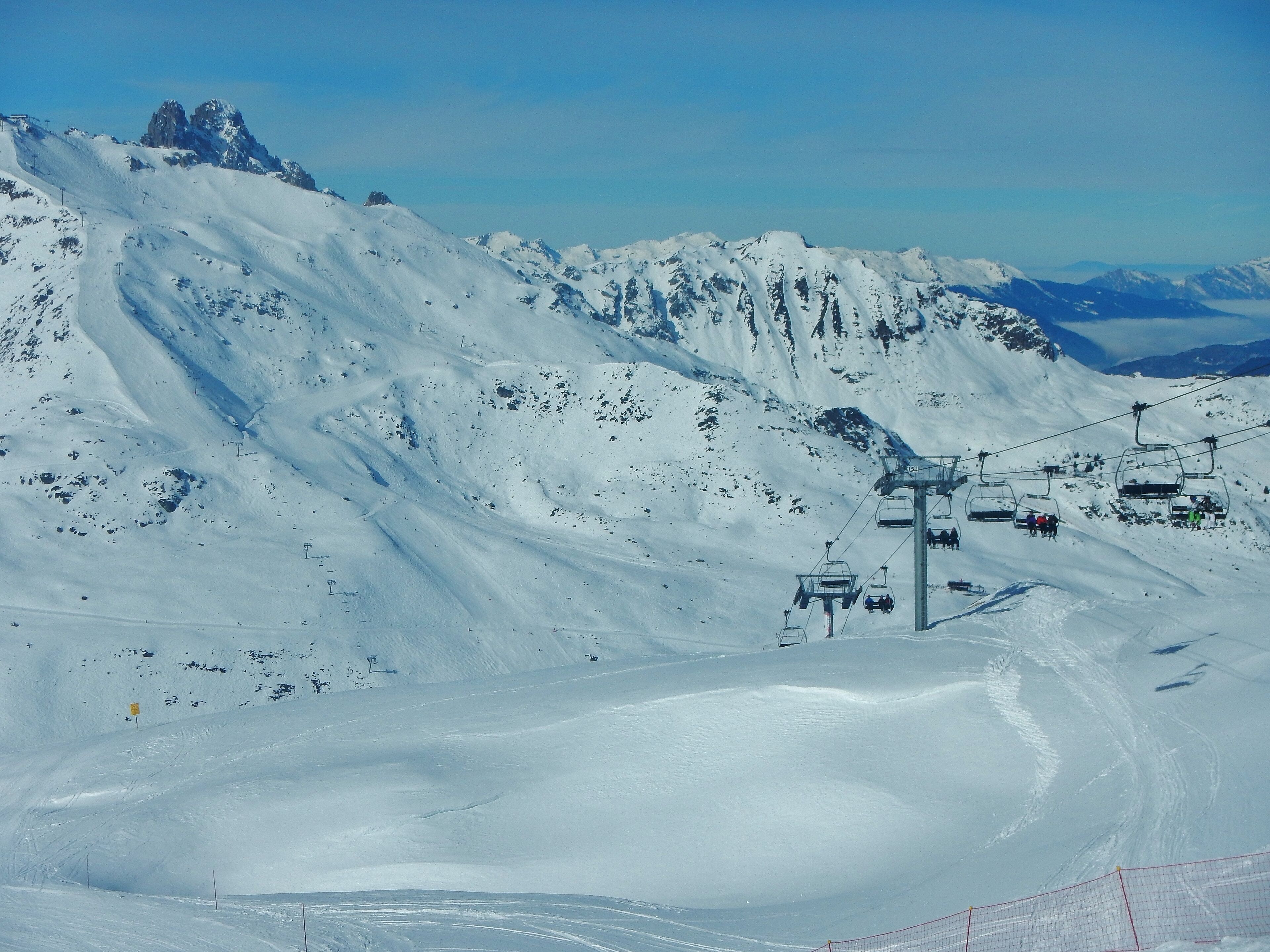 A snowy mountain landscape with ski lifts and a clear sky.
