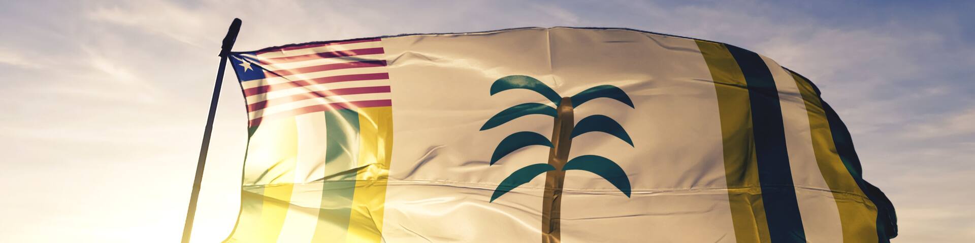 Grand Kru county of Liberia flag waving on the top sunrise mist fog