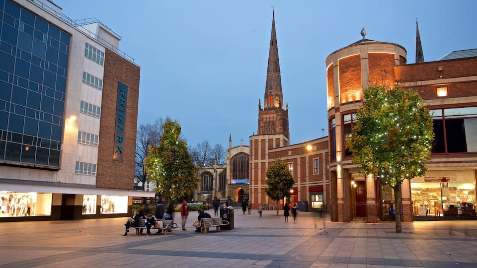 A city square with a church spire, modern buildings, and Christmas trees.