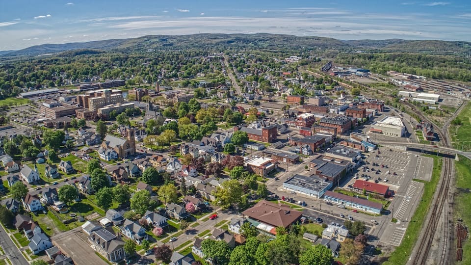 An aerial view of a town with a mix of residential and commercial buildings, a church, and a railway track.