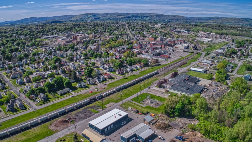 An aerial view of a town with residential areas, industrial buildings, and a train track.