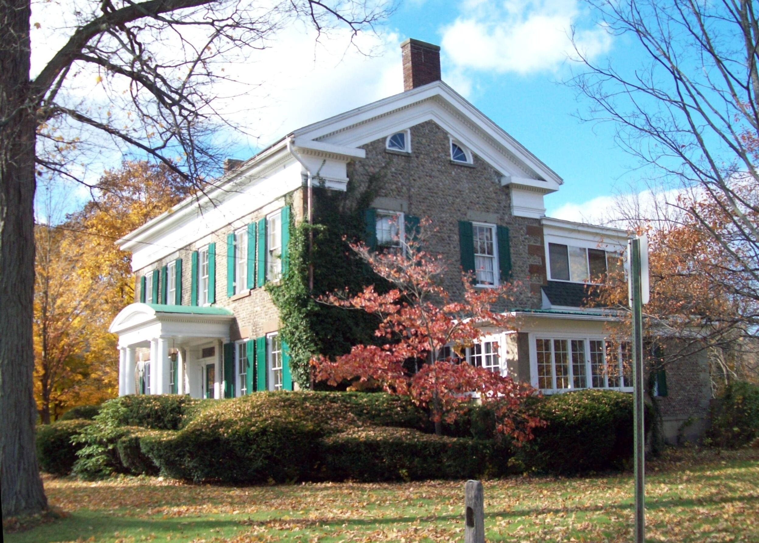 A large, two-story house with green shutters and a brick facade.