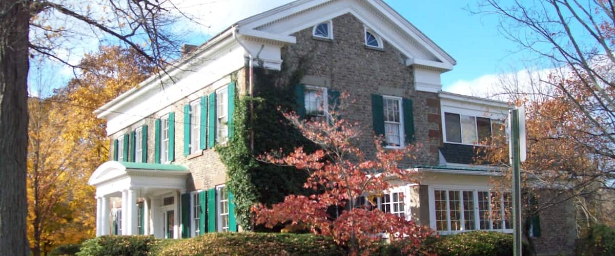 A large, two-story house with green shutters and a brick facade.