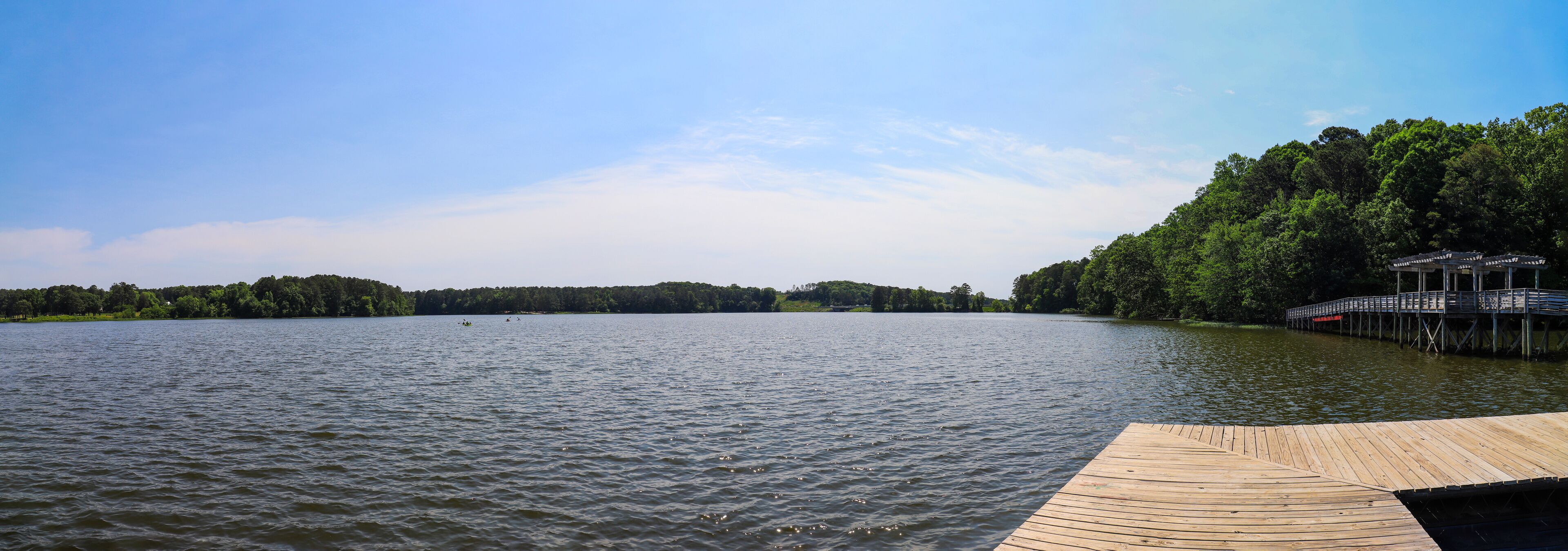 A calm lake with a wooden dock and a pier extending into the water.