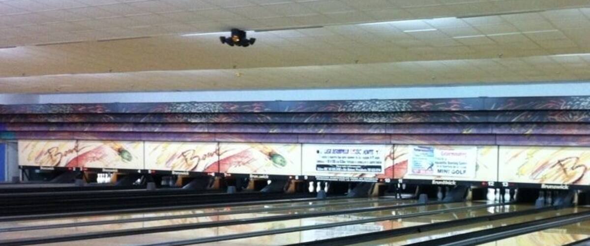 A bowling alley with multiple lanes and a colorful mural on the back wall.
