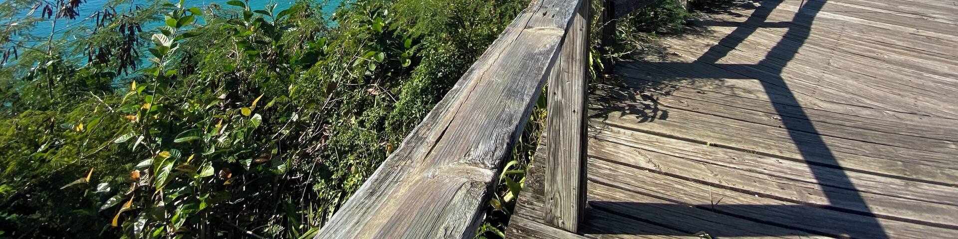 A wooden boardwalk overlooking a beach with a pier extending into the ocean.
