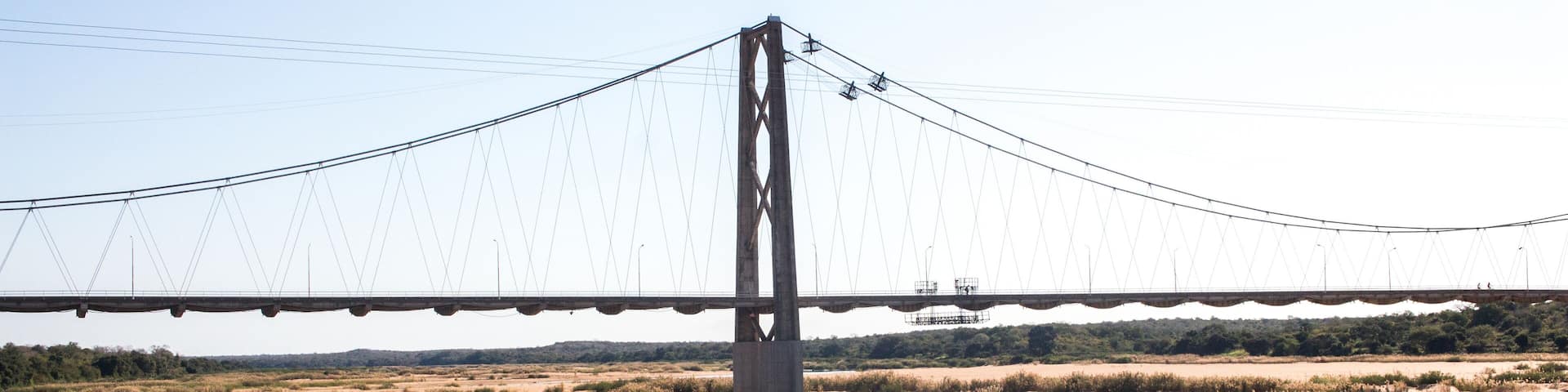 A bridge over a river with dry land and sparse vegetation.