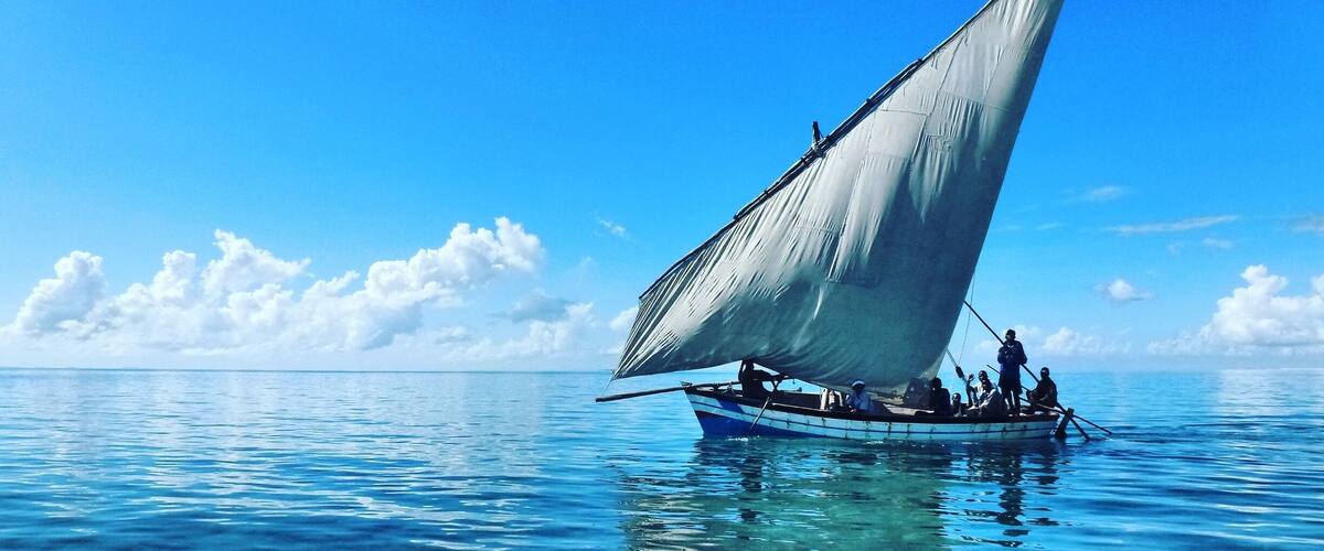 A sailboat with a large sail on a clear blue sea.