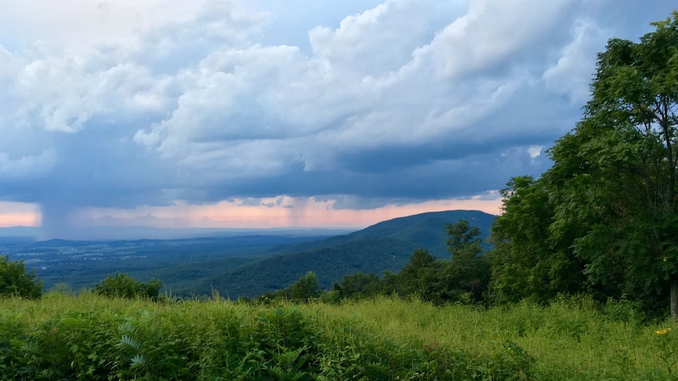 A lush green landscape with rolling hills and a cloudy sky.