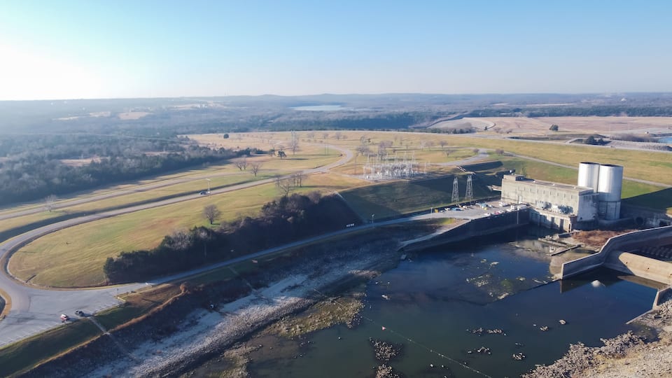 A dam with water reservoirs, a highway, and surrounding fields.