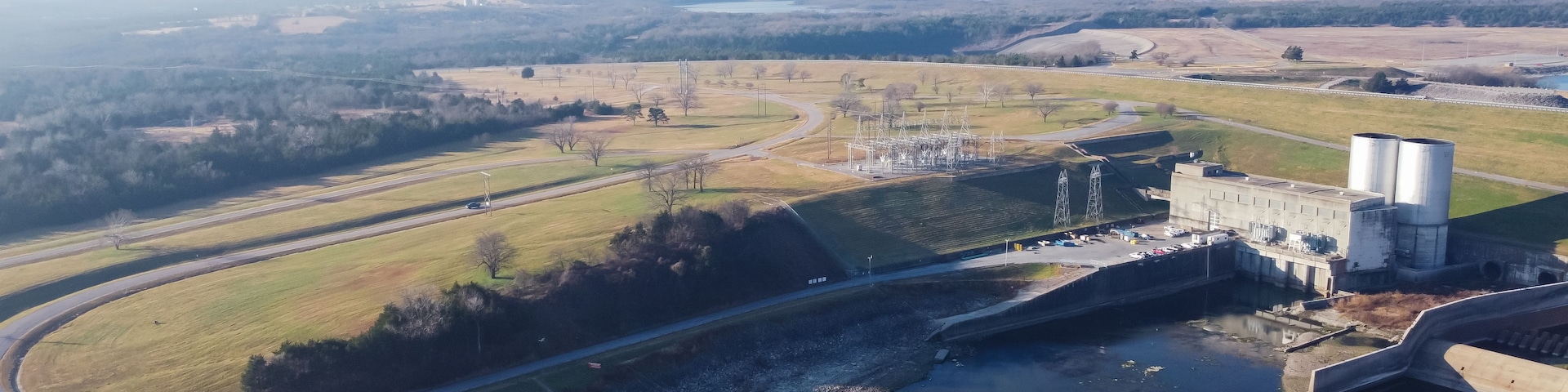 A dam with water reservoirs, a highway, and surrounding fields.