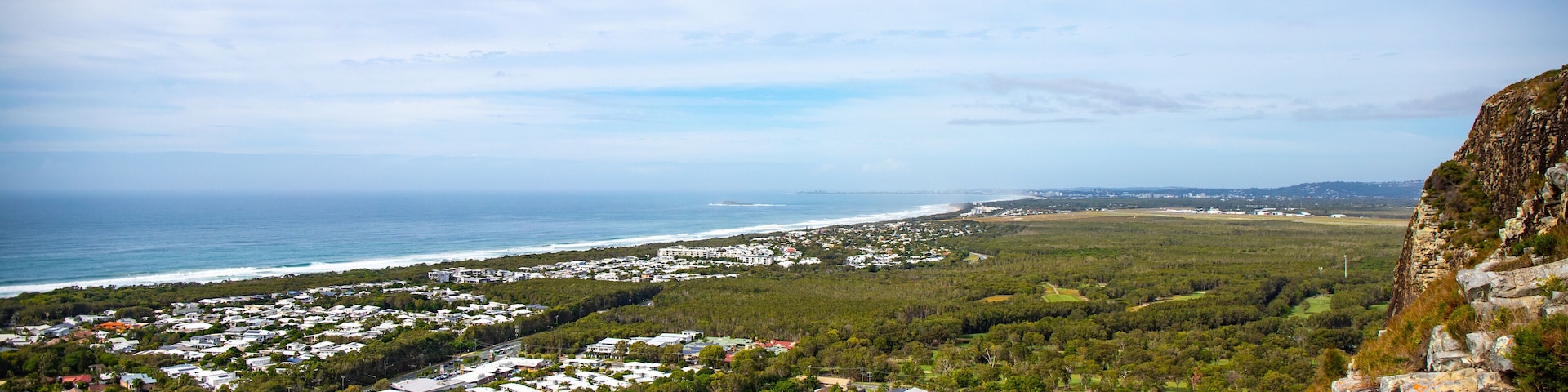 A coastal town with houses, a beach, and a cliff.