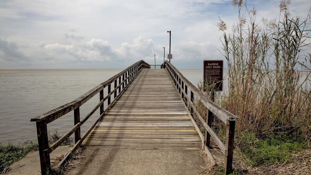 A wooden pier extending into a body of water, with a sign indicating 'DAPI CITY PARK'.