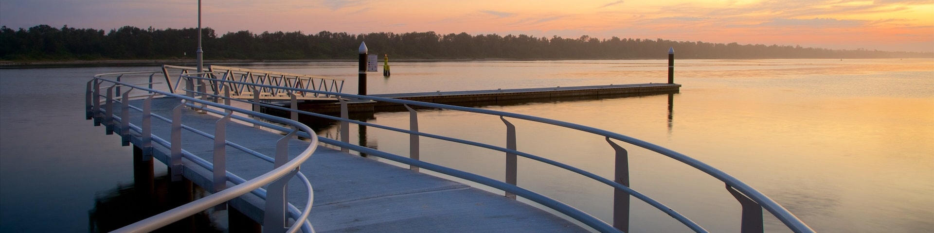 A pier extending into calm water with a sunset in the background.