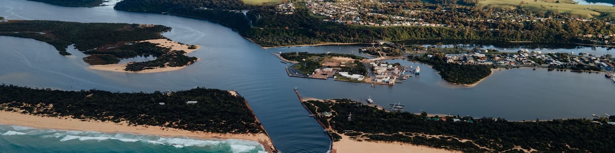 An aerial view of a coastal area with a beach, a river, and a town.