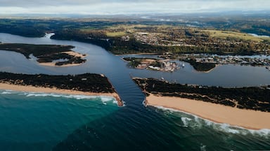 An aerial view of a coastal area with a beach, a river, and a town.