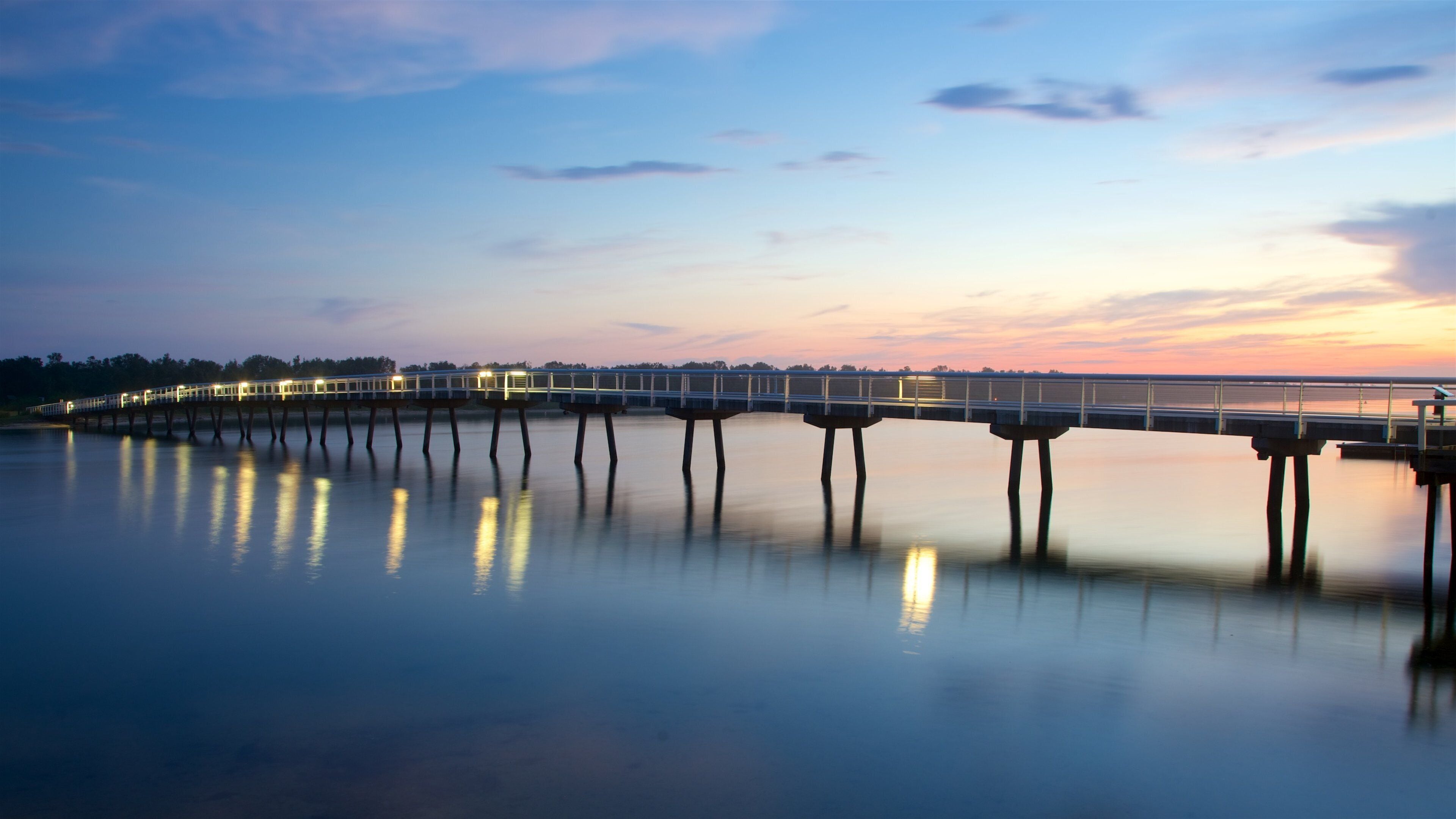 Lakes Entrance ofreciendo una puesta de sol, una bahía o puerto y un puente