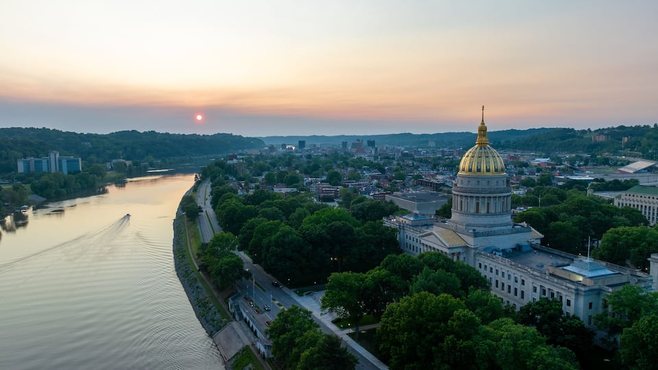 A cityscape with a river, a prominent golden-domed building, and surrounding greenery.