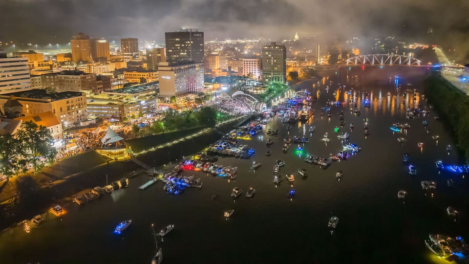 A river with boats and a cityscape with illuminated buildings at night.