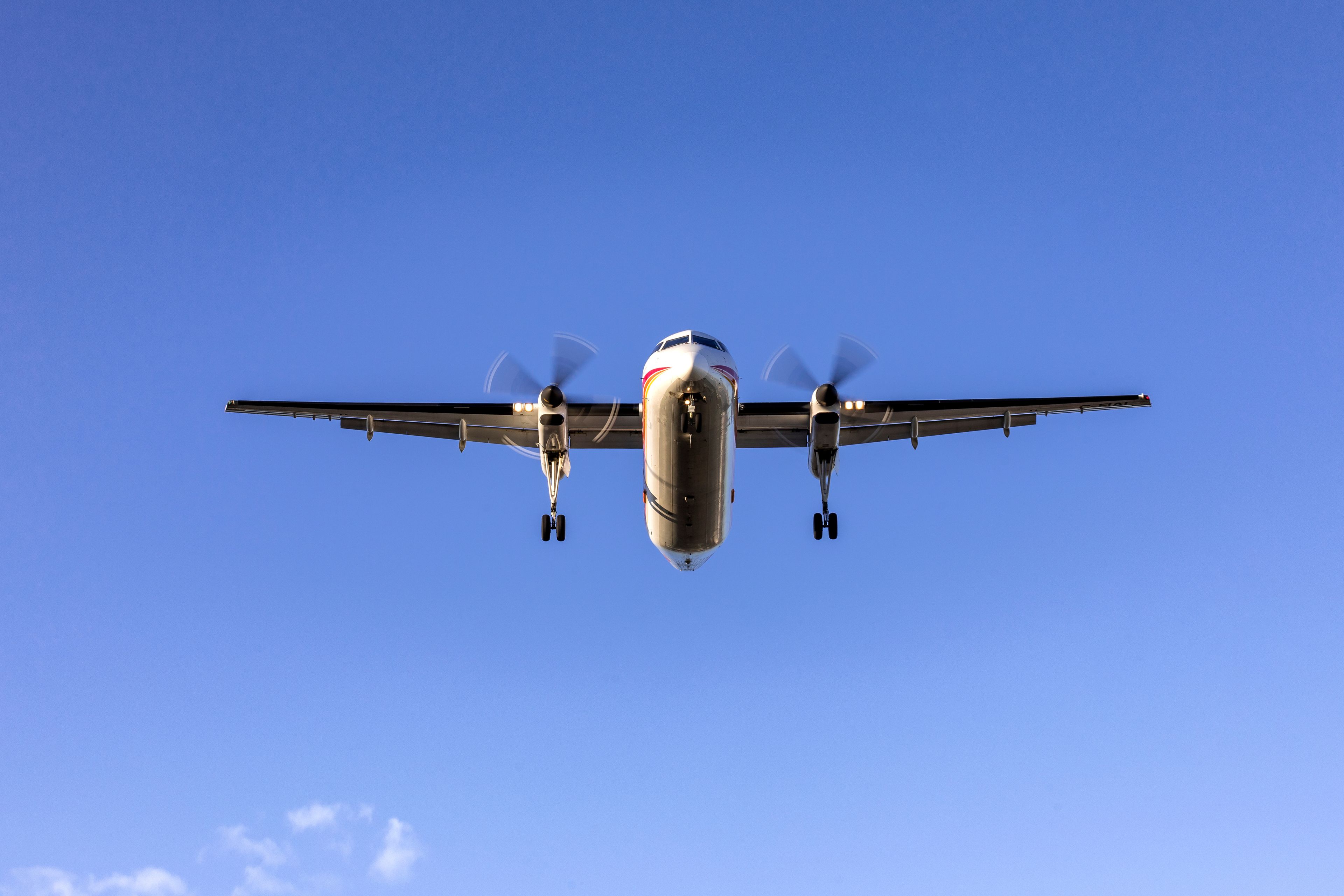 A large, four-engine propeller aircraft in flight against a clear blue sky.