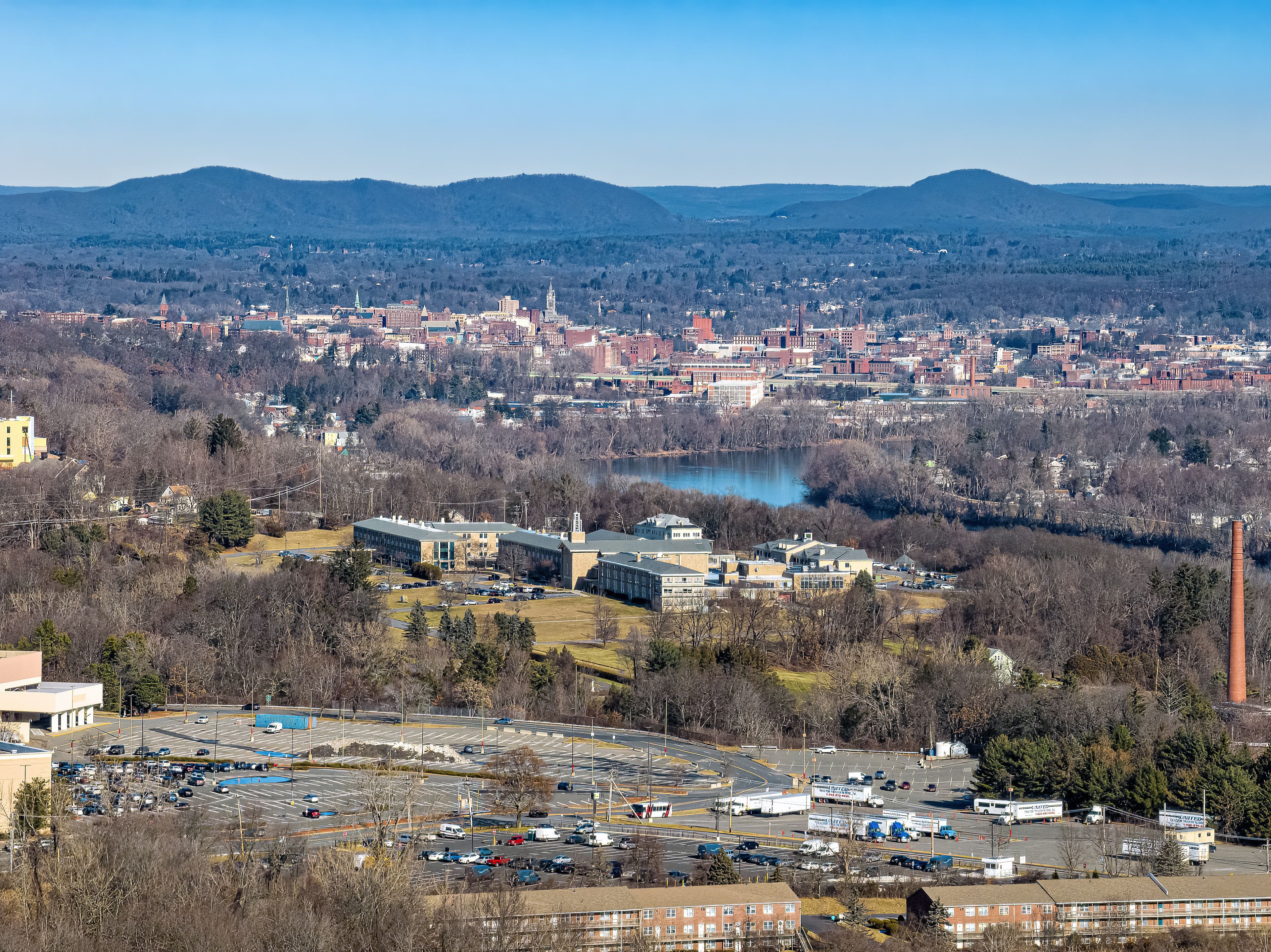 A cityscape with a large body of water, a prominent building with a tower, and a mountainous backdrop.