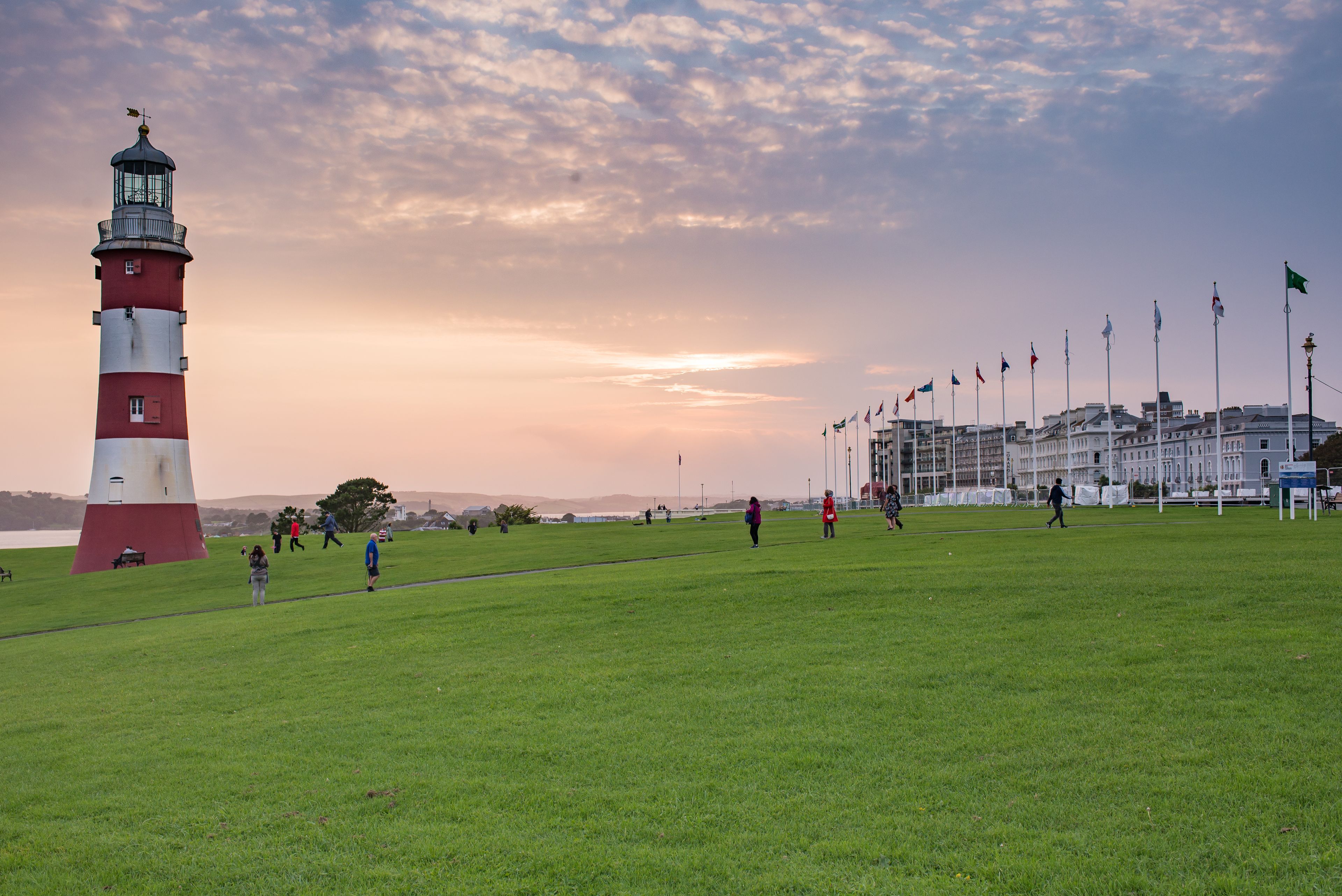 A lighthouse, a grassy field, and a row of flags.