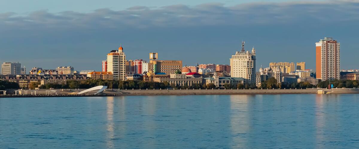A city skyline with various buildings, including a prominent tower and a bridge over a body of water.