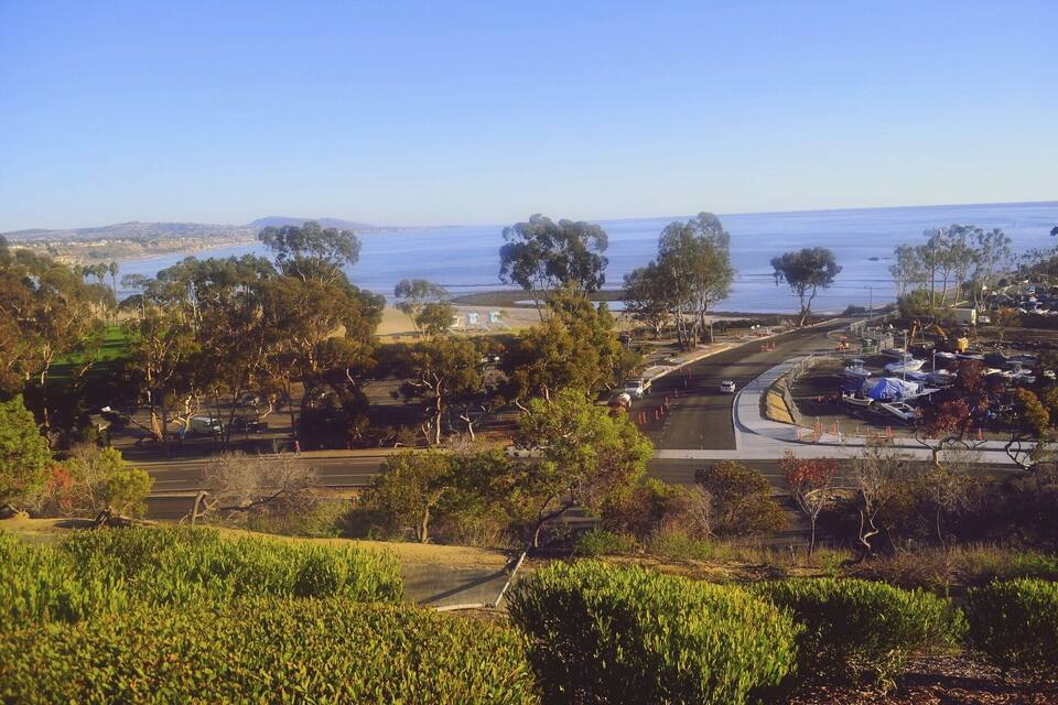 Uma estrada costeira com vista para o oceano e colinas ao longe.