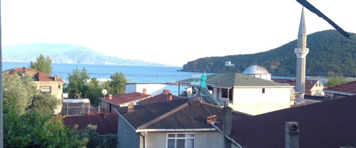 A coastal town with a mosque, a sea view, and mountains in the background.