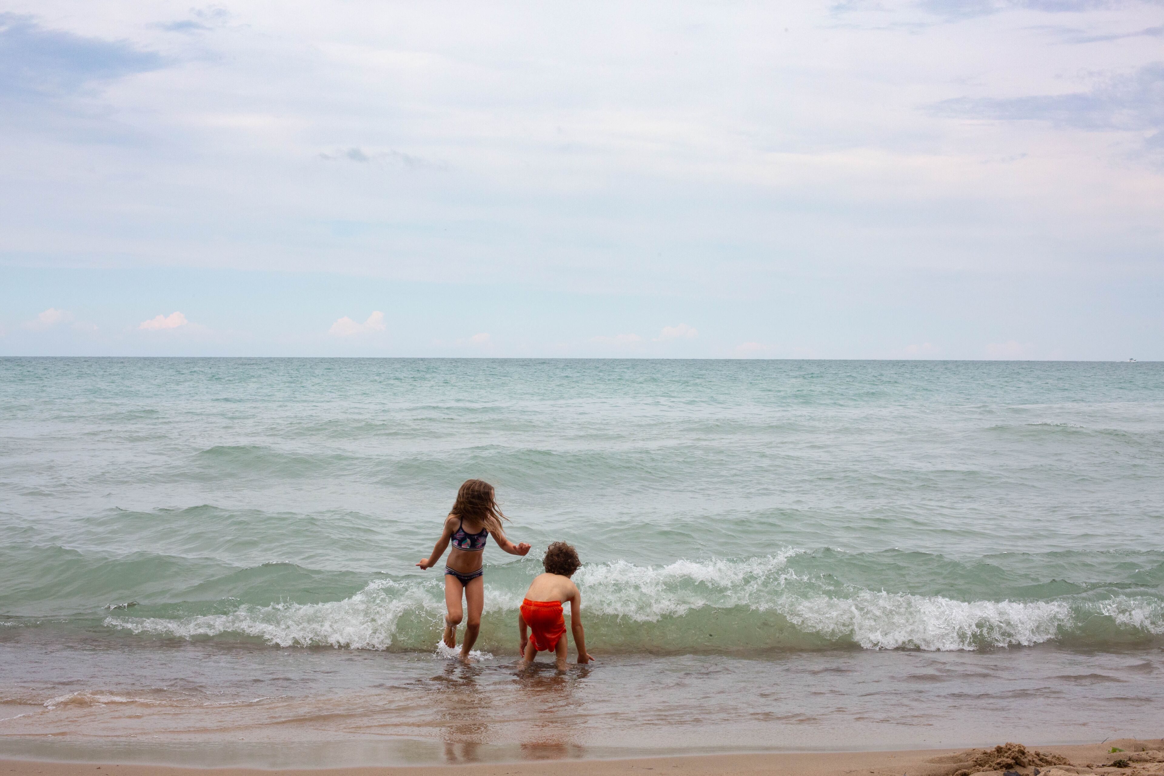 Duas crianças brincando na água rasa da praia.