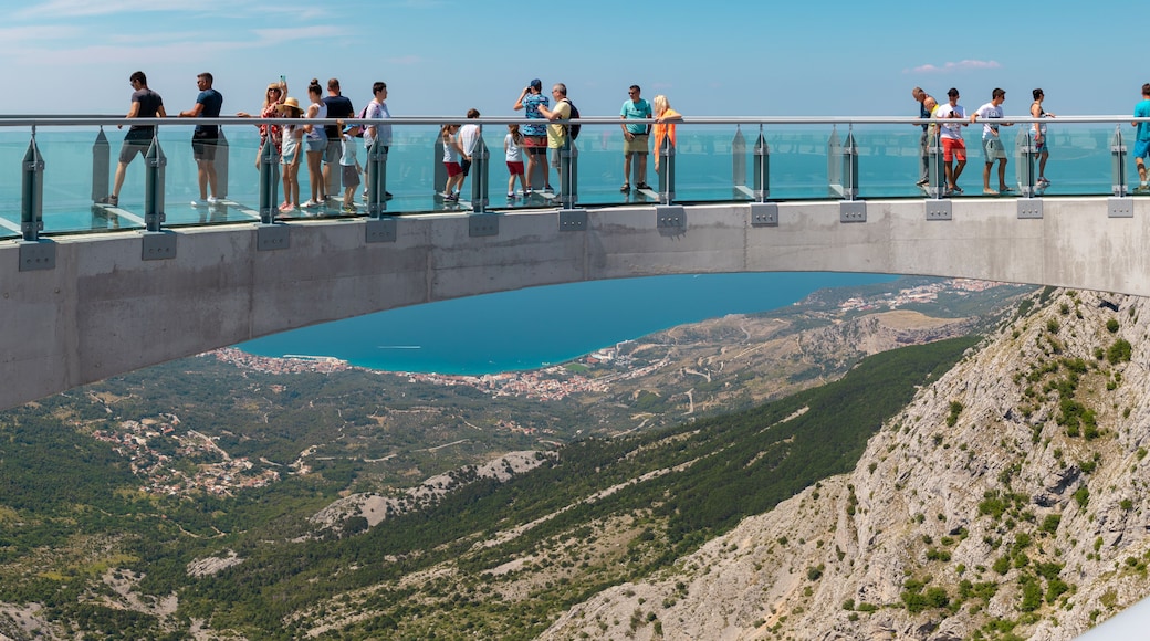 Tourists walking accross the newly built skywalk on Biokovo mountain. Wide view from the entrance, towns and the sea visible in far distance