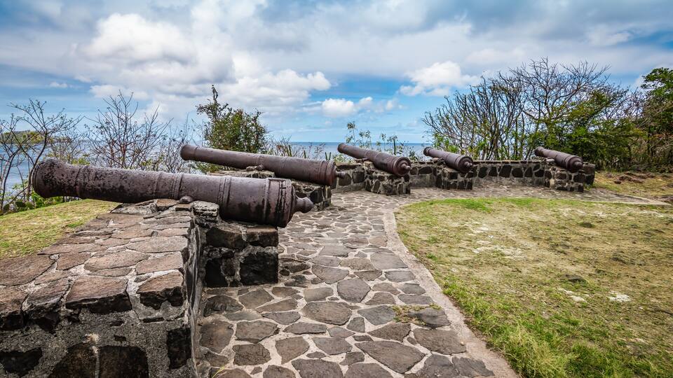 A stone pathway leading to cannons overlooking a body of water.