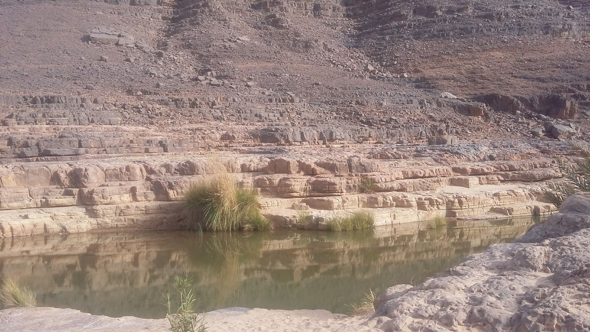 A rocky landscape with a small body of water reflecting the surrounding cliffs.