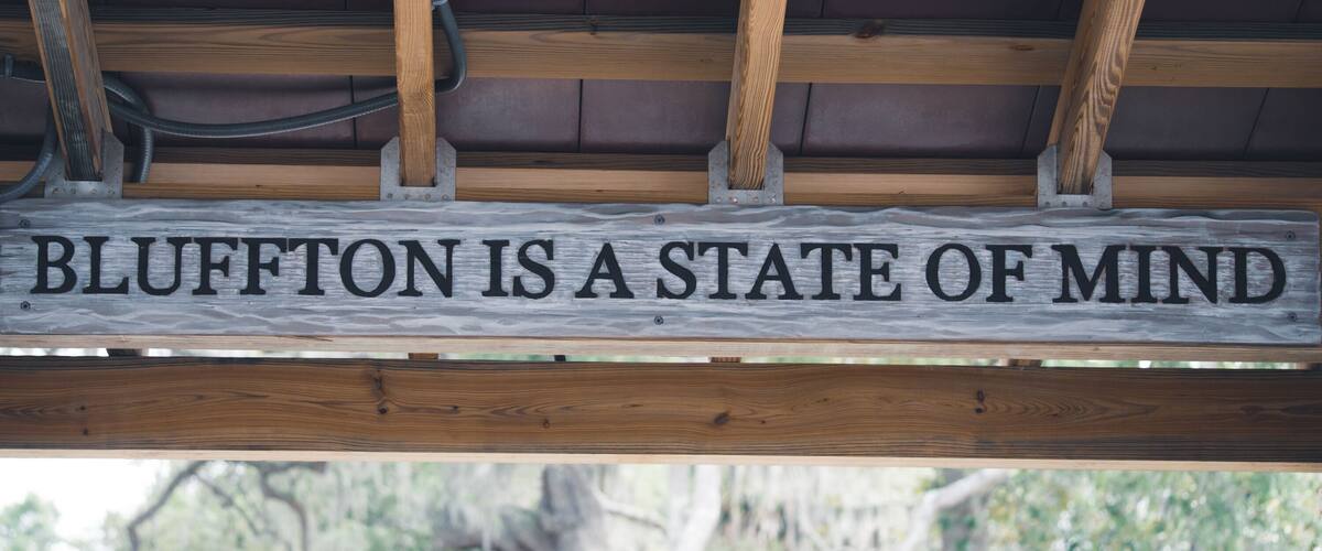 A wooden sign with the text 'BLUFFTON IS A STATE OF MIND.'