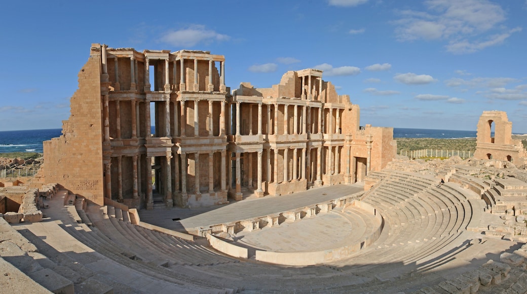 Ancient ruins with a large amphitheater and columns.