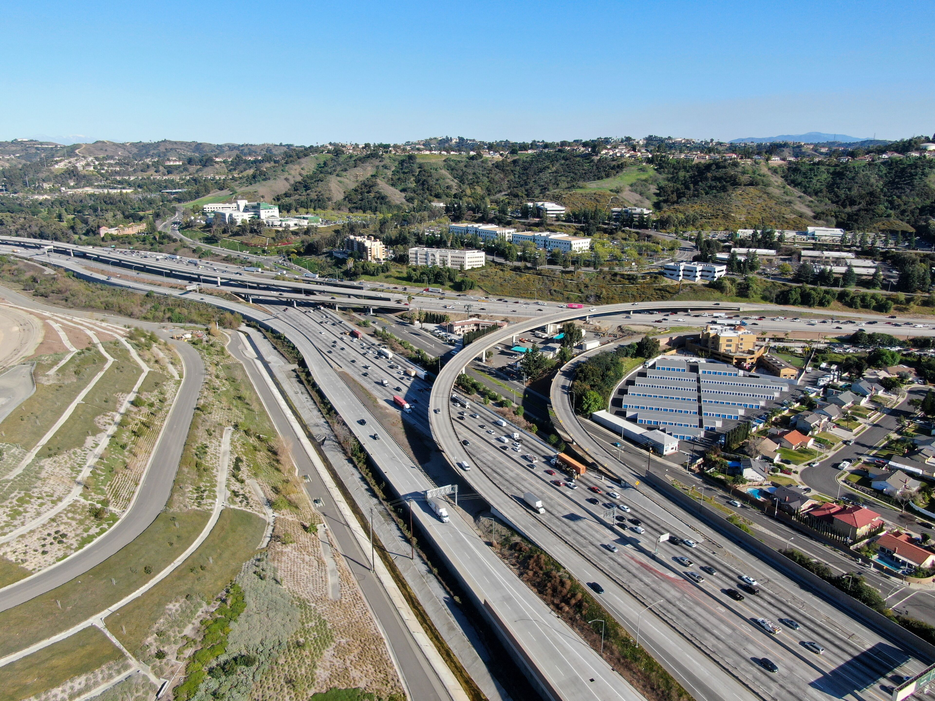 Aerial view of highway with traffic surrounded by houses in Diamond Bar City. Intersection city transport road with vehicle movement. Eastern Los Angeles, California, USA.