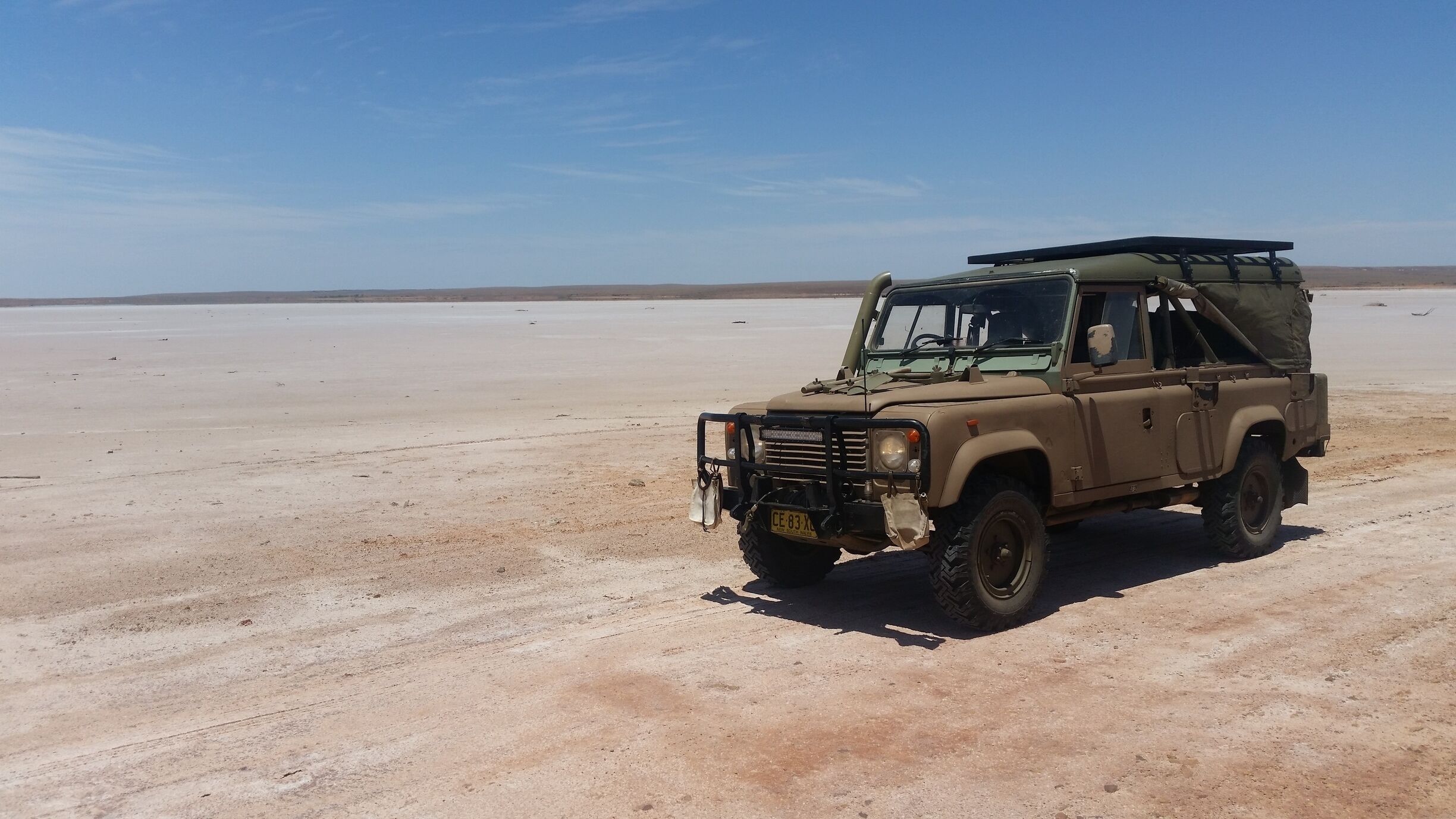 A beige off-road vehicle parked in a barren desert landscape.