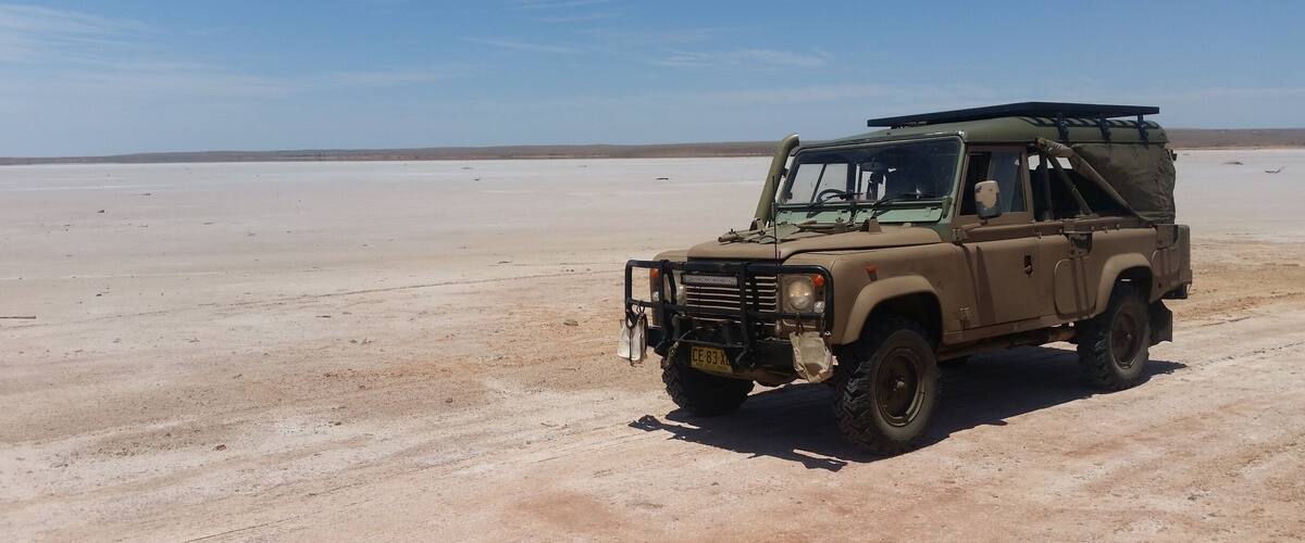 A beige off-road vehicle parked in a barren desert landscape.
