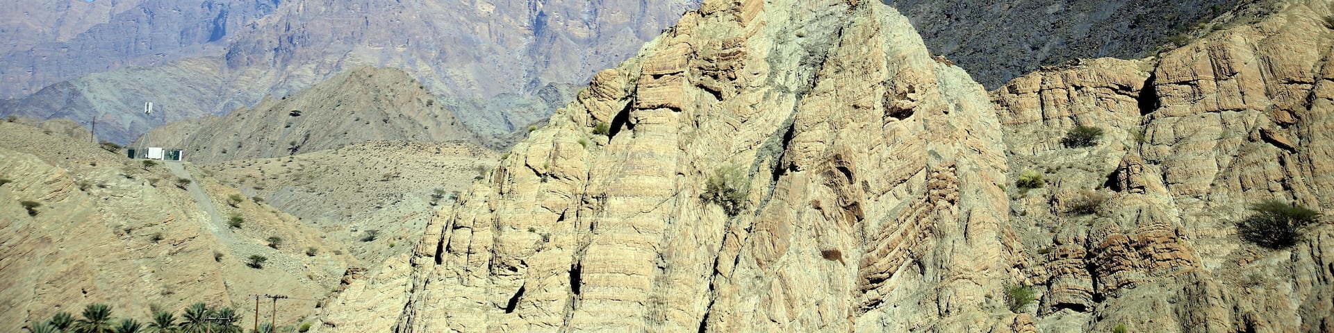 A mountainous landscape with a clear sky and a crescent moon.