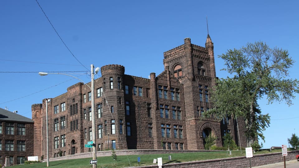 A large, historic brick building with arched windows and a tower.