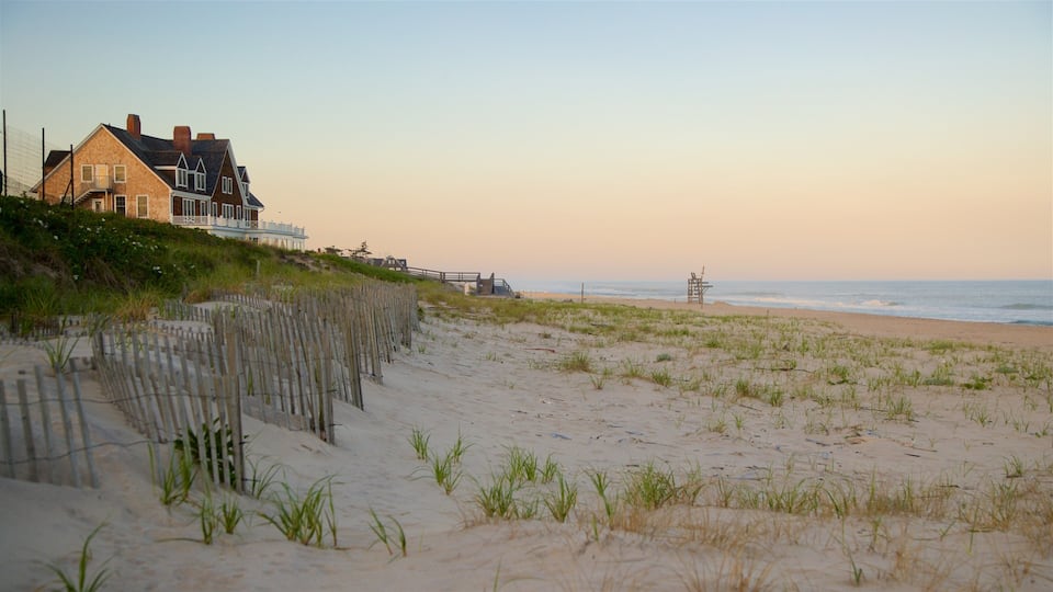A beach with a wooden fence, a lifeguard tower, and a house with a balcony overlooking the ocean.