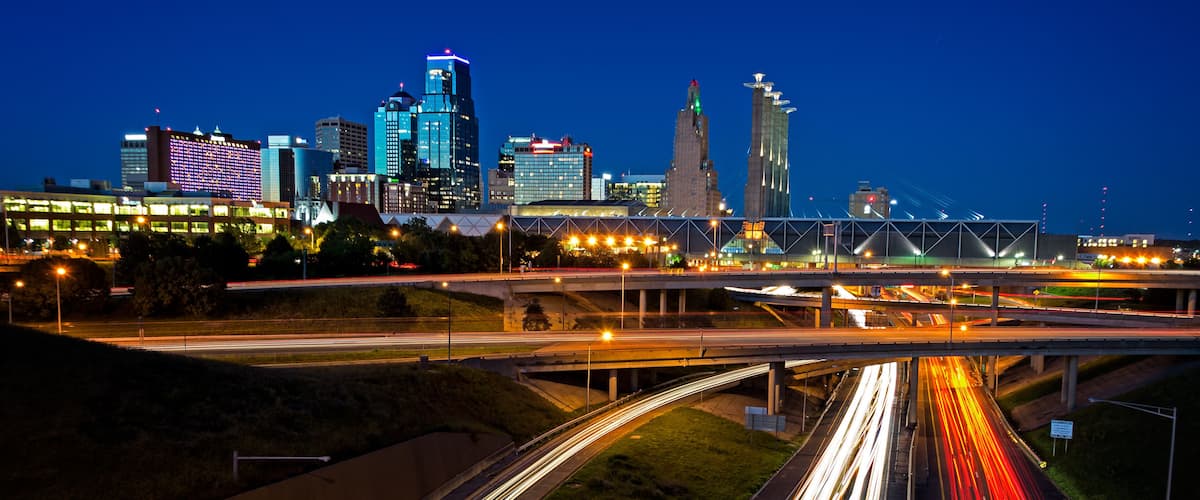 A city skyline with illuminated buildings and a multi-level highway with light trails.