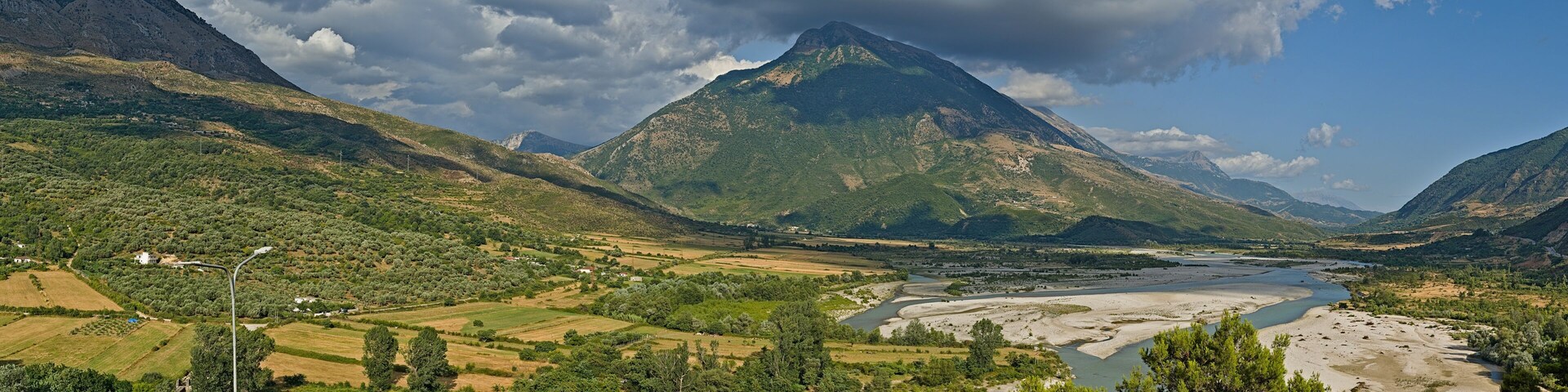 Un paisaje montañoso con un río, campos y casas dispersas.