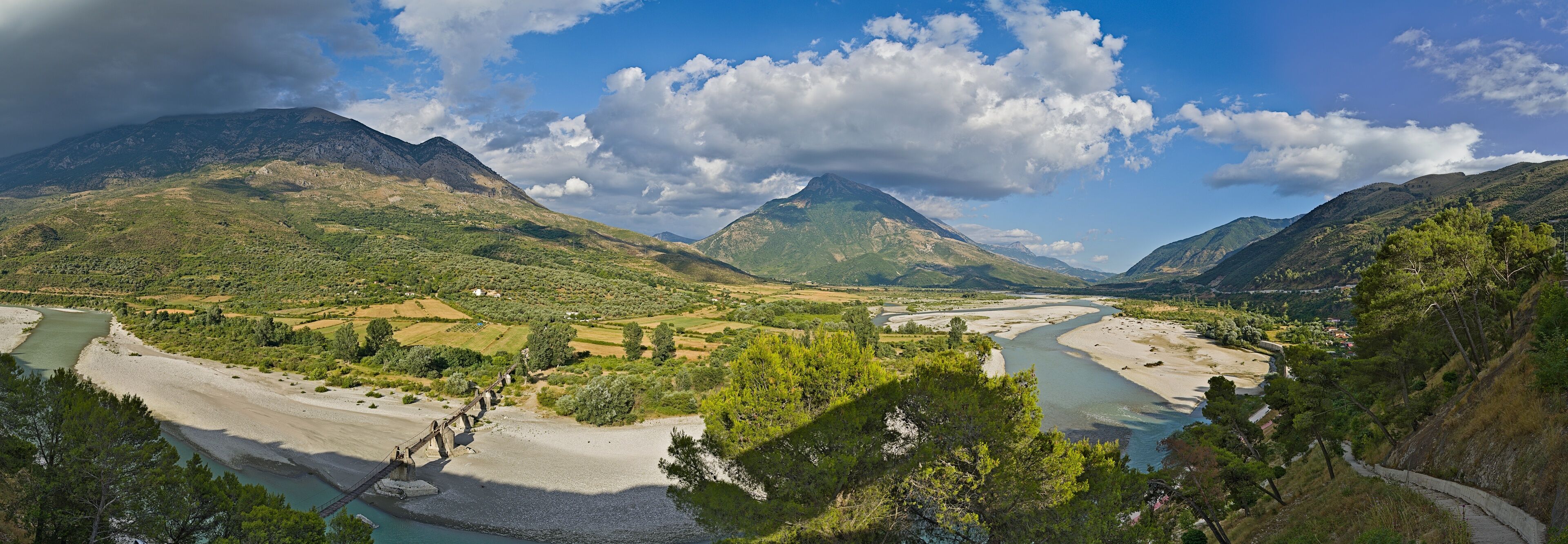 A river flowing through a mountainous landscape with a bridge and a winding road.