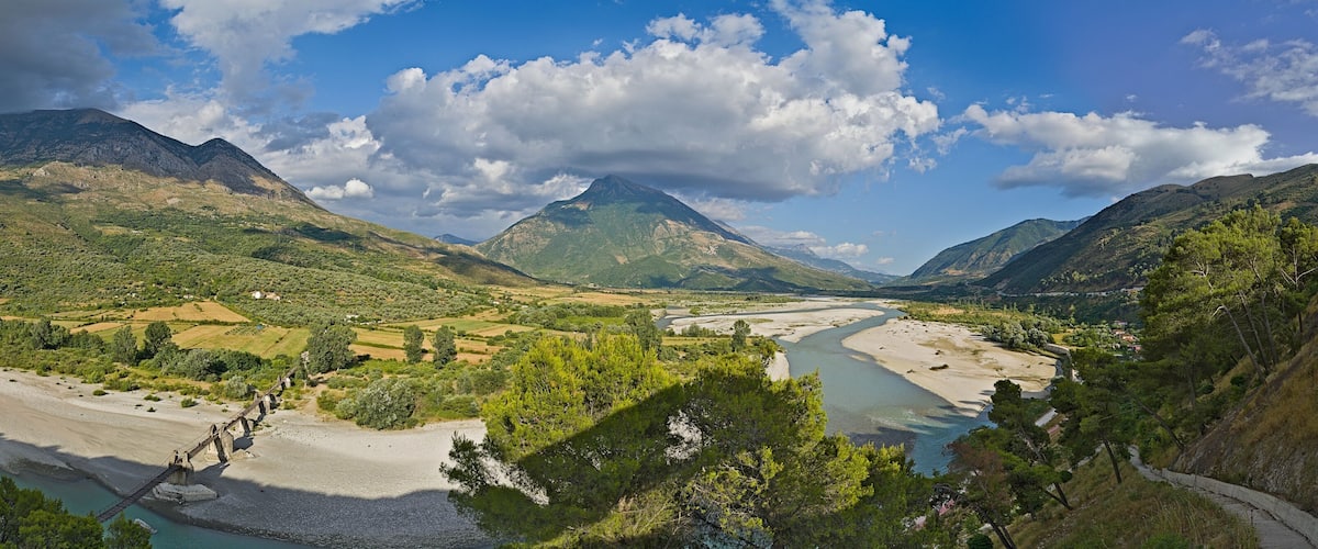 A river flowing through a mountainous landscape with a bridge and a winding road.